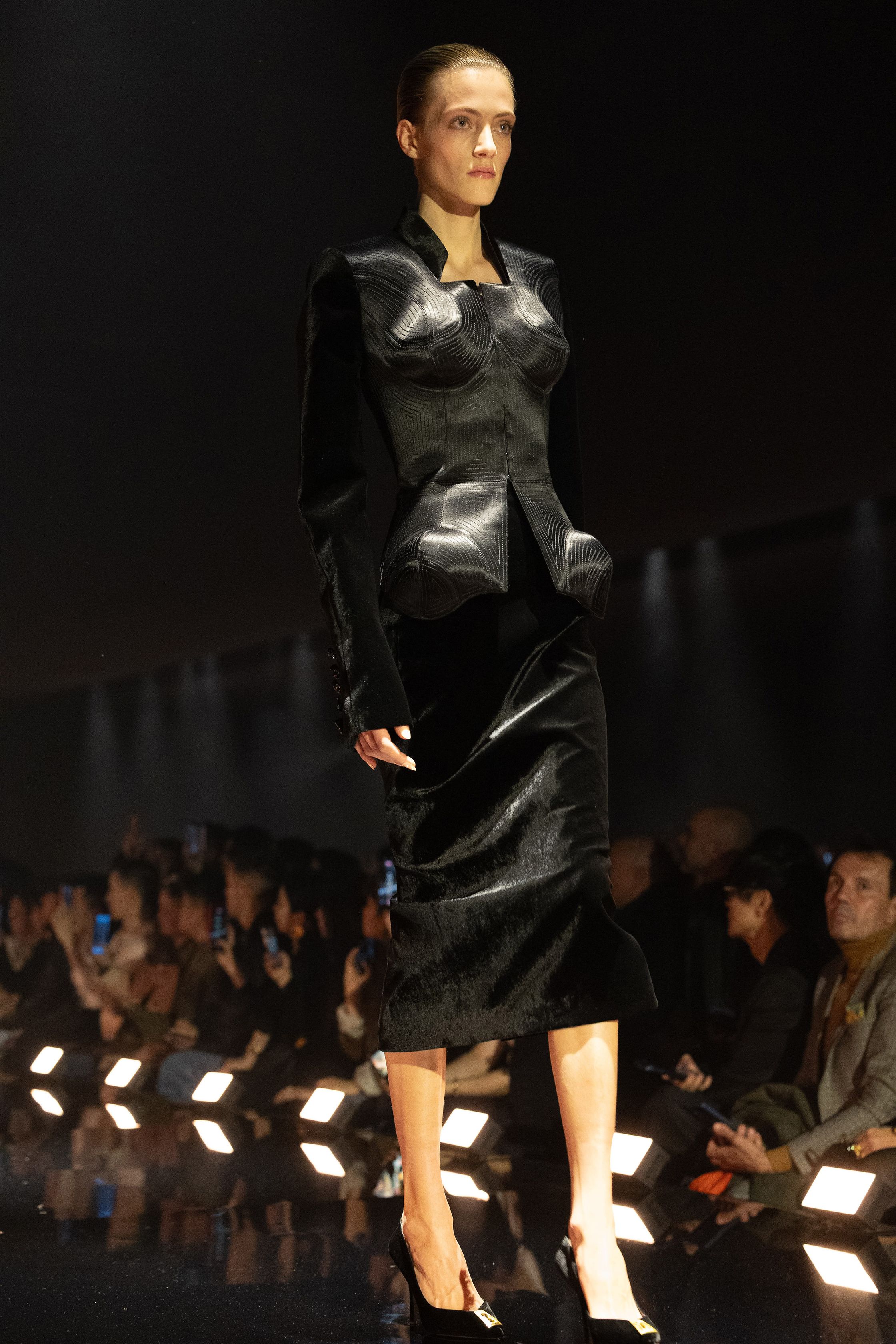 Schiaparelli 2026秋冬系列延续品牌标志性的超现实主义美学，在金色灯光的T台上呈现极具雕塑感的廓形。沙金色与黑金色成为主调，褶皱礼服、雕塑式西装与高腰裙装强化身体线条。经典的金属装饰、夸张肩线以及精致刺绣细节构成强烈视觉符号，使整场秀既华丽又充满戏剧张力。设计师通过结构与面料的张力对比，让高级定制的艺术精神融入现代女性衣橱-顽石频道趋势研究